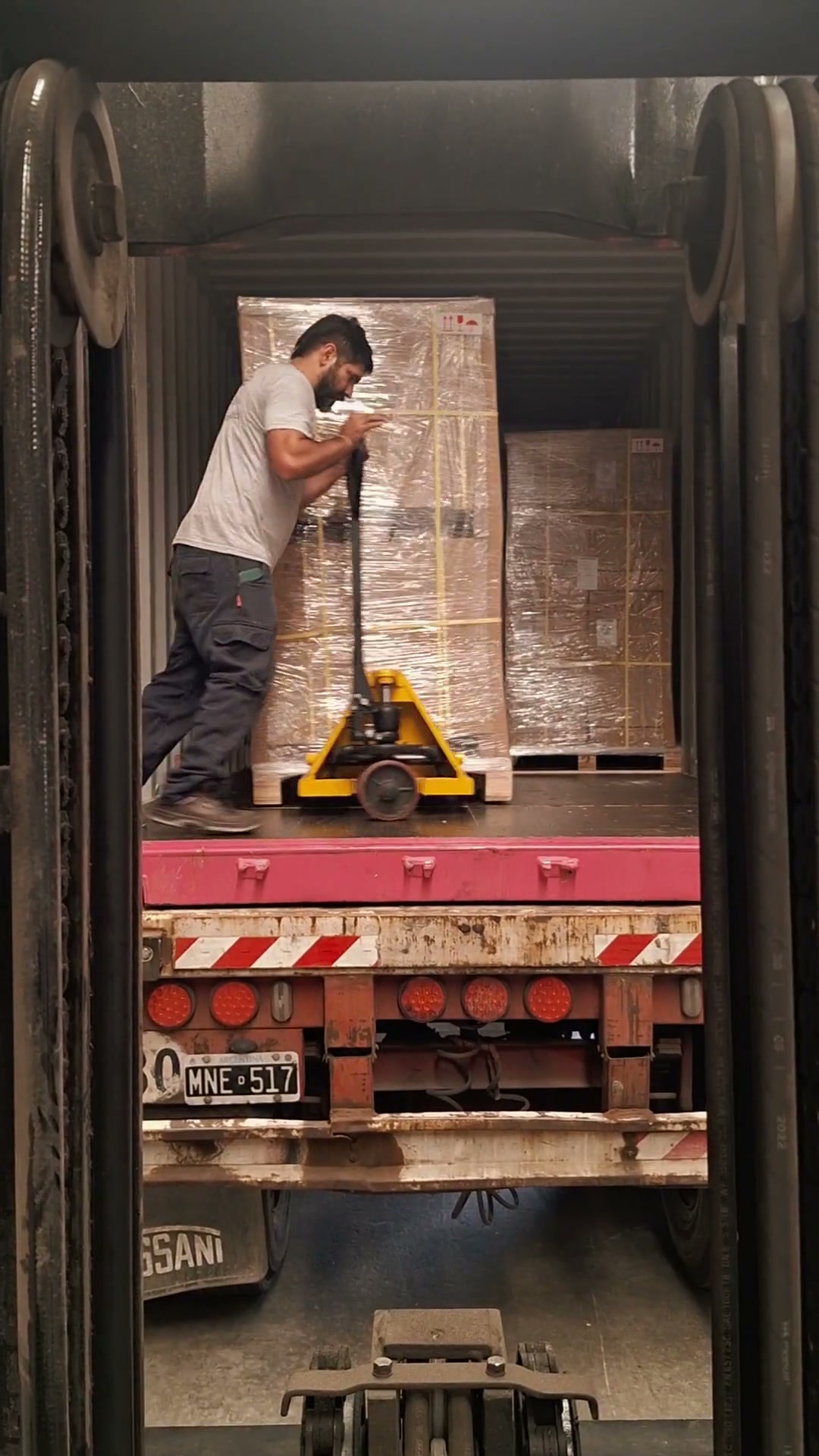 Operario descargando un pallet con zorra manual desde un contenedor para NCR Argentina