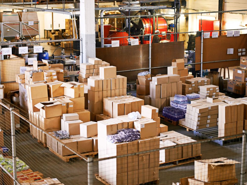 Vista aérea de un depósito con cajas de cartón apiladas sobre pallets, listas para su almacenaje y despacho