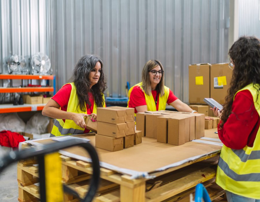 Tres operarias con chaleco refractario armando y revisando cajas de pedidos sobre un pallet